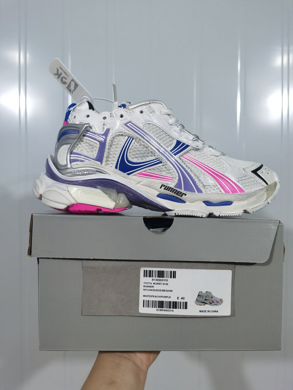 Balenciaga 6120 runner sneaker in white with blue, purple, and pink accents, shown above its box.