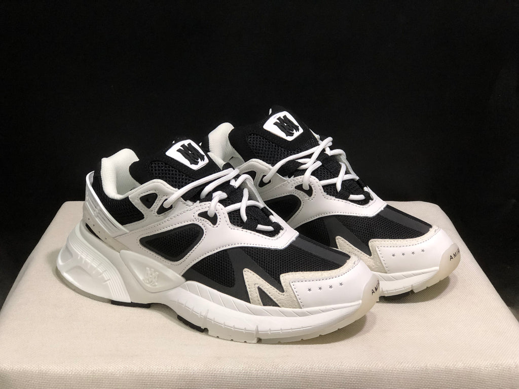 Front three-quarter view of the white and black AMIRI MA Runner pair.