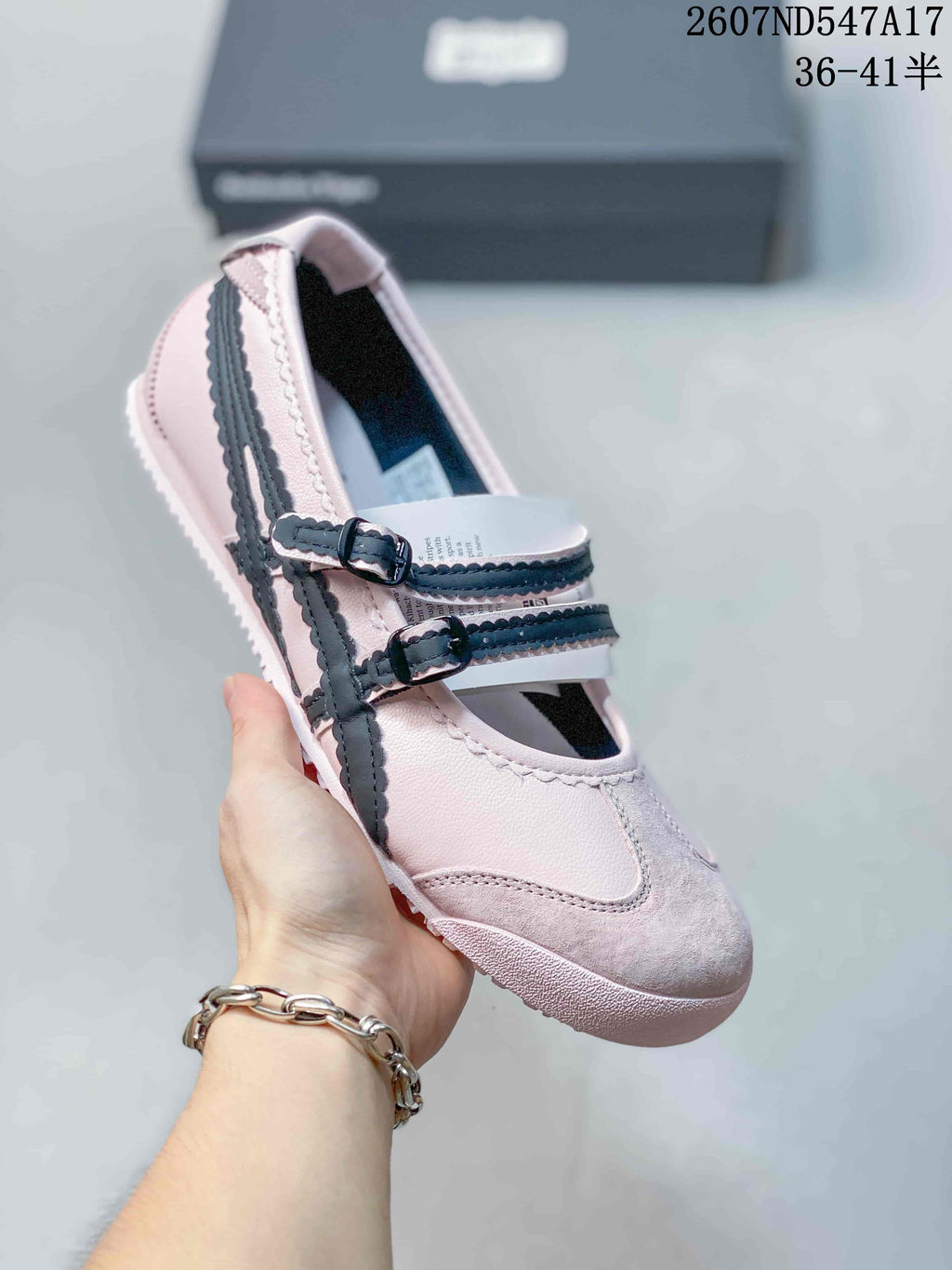 Angled close view of one pale pink Mary Jane sneaker with double buckle straps and dark side stripes.
