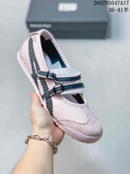 Angled close view of one pale pink Mary Jane sneaker with double buckle straps and dark side stripes.