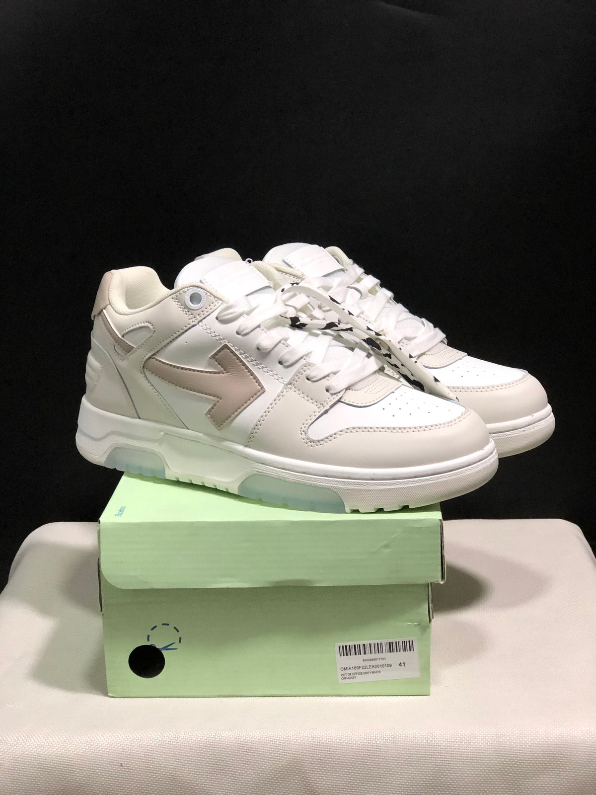 Pair of white low-top sneakers displayed on a pale green shoe box; the box label visibly shows size 41.