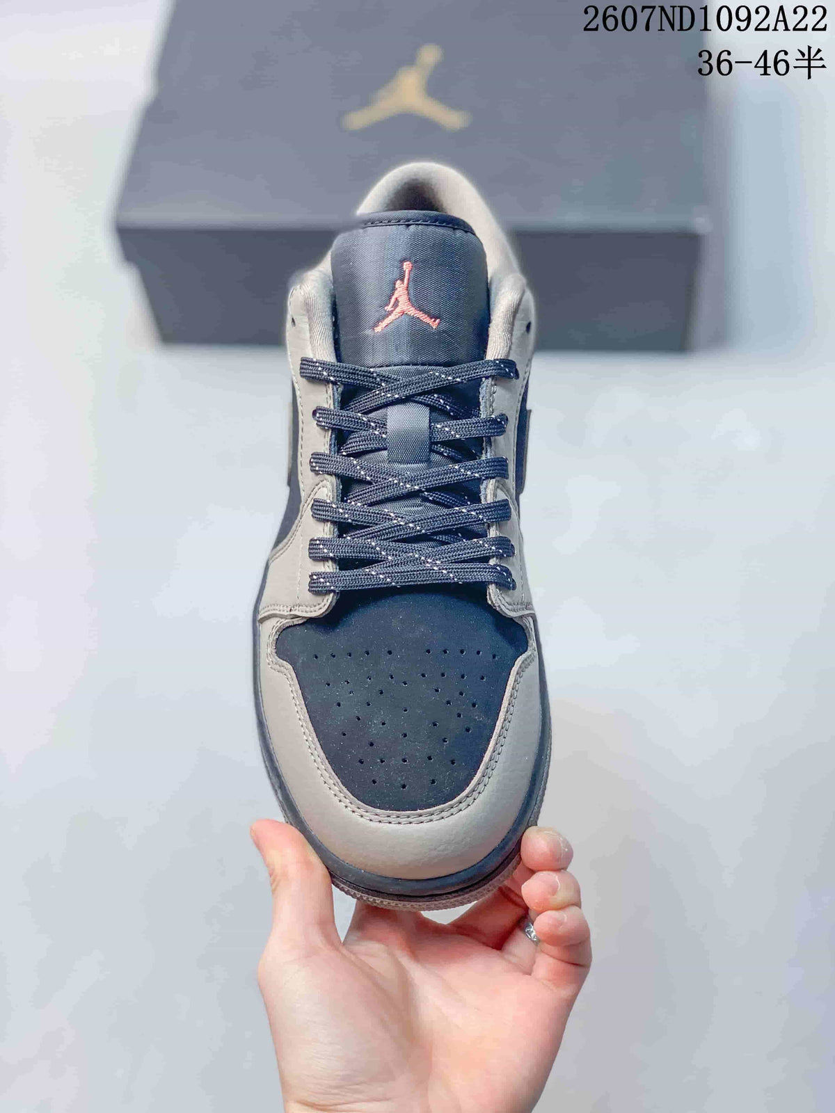 Top view of a low-top sneaker showing the dark perforated toe box, contrasting overlays, laces, and Jordan tongue logo.