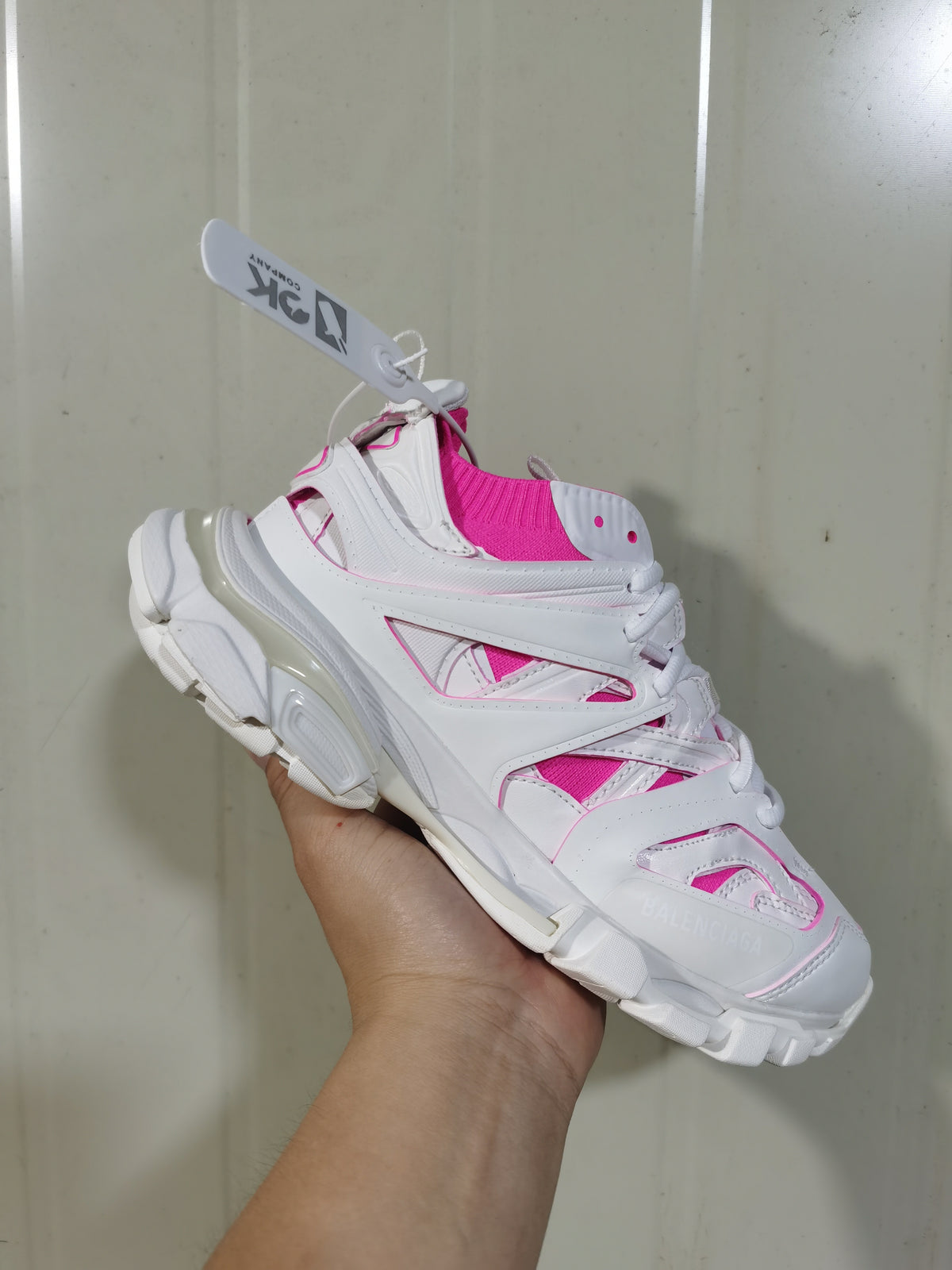 Close angled view of the white and fluorescent pink Balenciaga sneaker, showing the knit sock collar, layered upper and lace fastening.