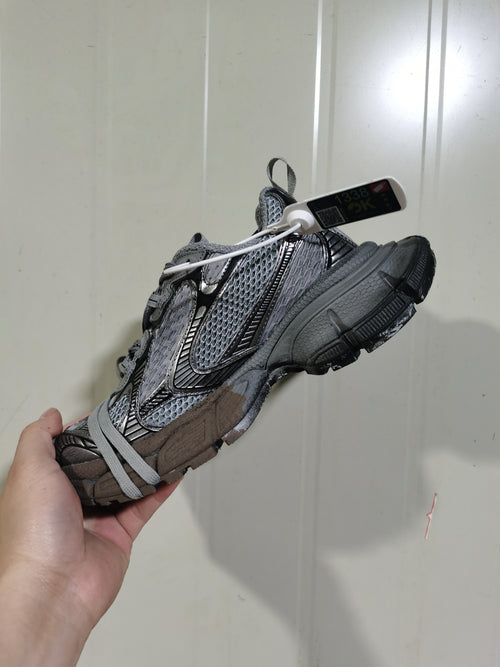Side view of the grey and black mesh sneaker showing layered overlays, laces, and chunky outsole.