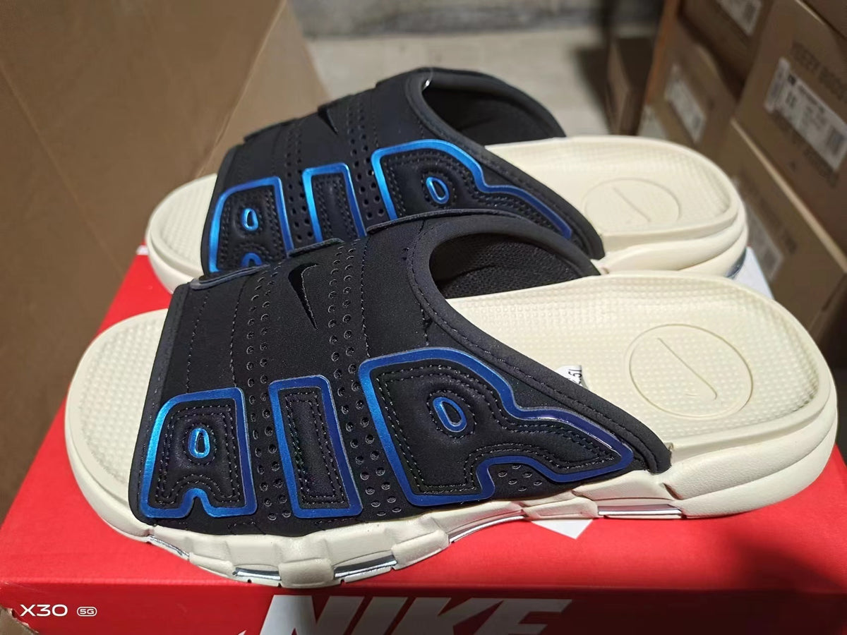 Black Nike Air-style slide sandals with blue outlined panel details and a light-colored segmented outsole.