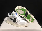 Angled view of one sneaker with the outsole exposed, showing green and black tread accents.