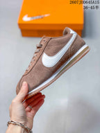 Side profile of the brown Nike sneaker showing the white Swoosh, white midsole, and gum-colored outsole.