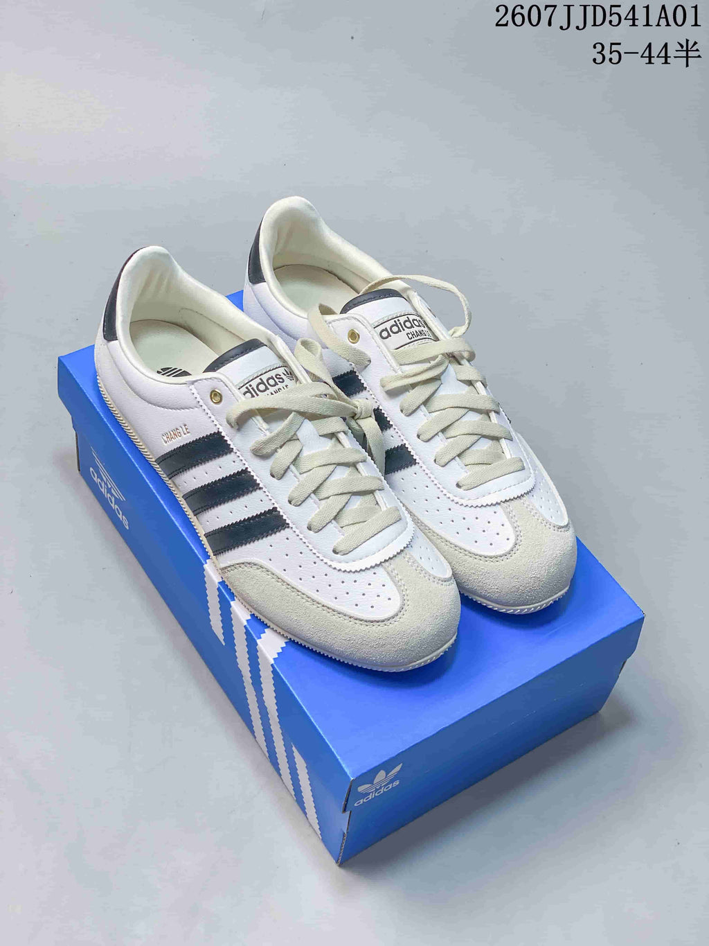 Pair of white Adidas Originals VS JOG 2.0 low-top sneakers with dark stripes and light textured toe overlays
