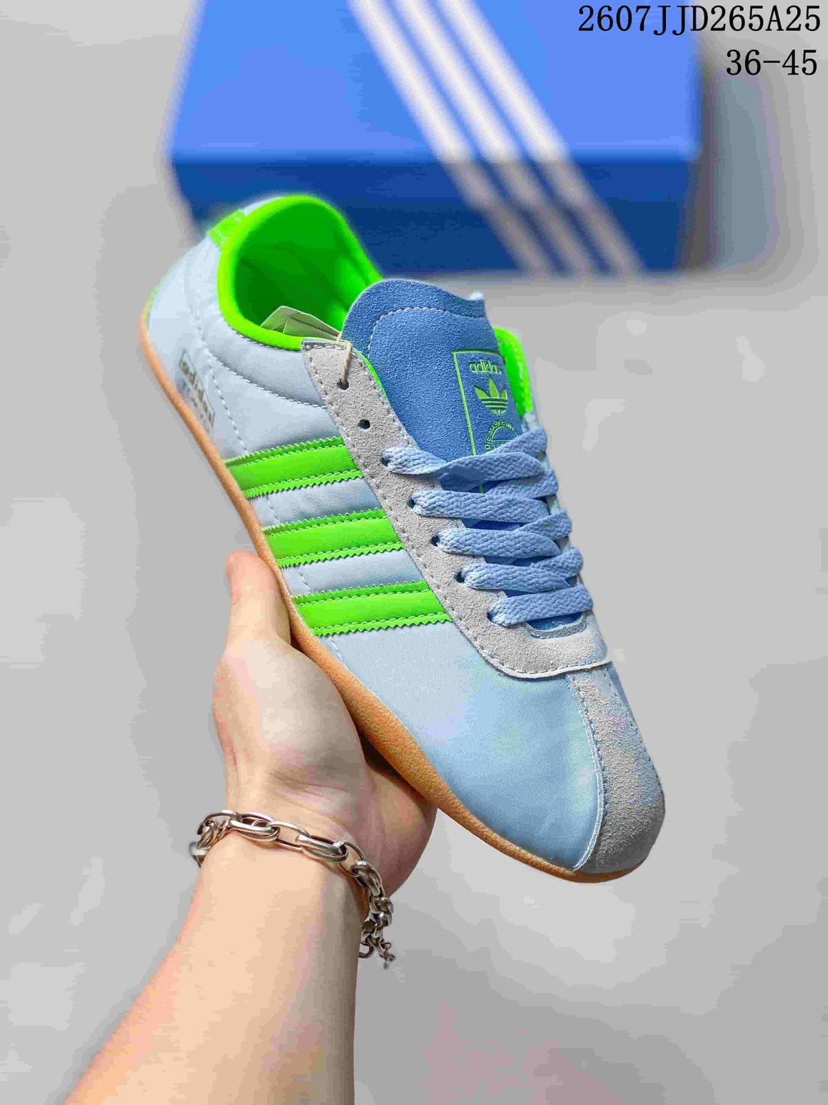 Angled side view of the light blue adidas sneaker with green stripes and bright green collar lining.