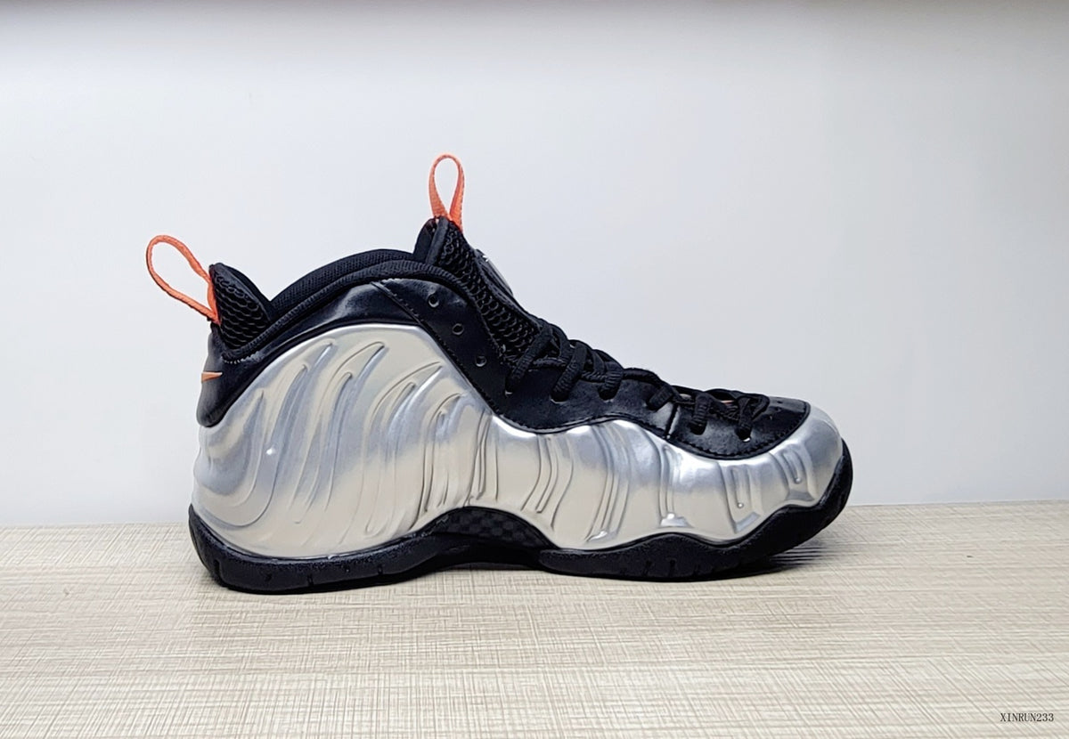 Side profile of a high-top sneaker with a silver molded-looking panel, black upper, and orange pull tab