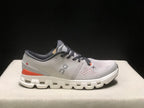 Side profile of one shoe showing the silver upper, orange heel accent, dark collar, and white outsole.