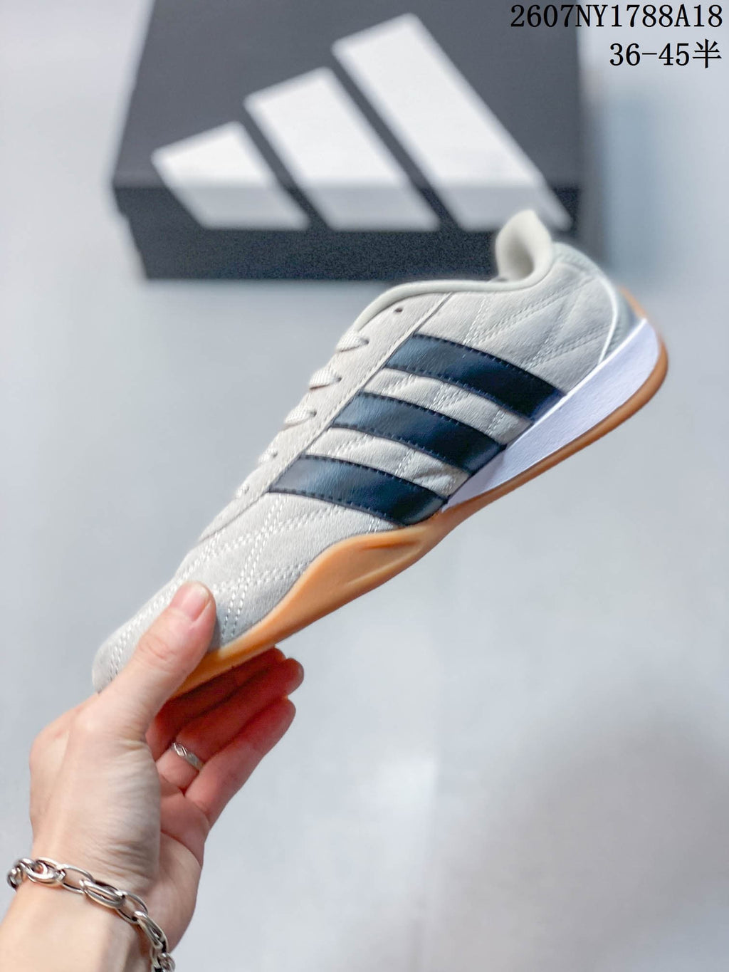 Side profile showing the light upper, dark three-stripe detailing, white midsole and gum outsole.