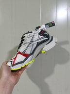 Side view of the Balenciaga Runner sneaker highlighting the white and grey upper, red overlays, black accents and fluorescent yellow outsole sections.