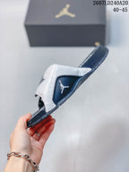Side view of the slide with its adjustable strap lifted, showing the navy side panel and Jordan branding detail.