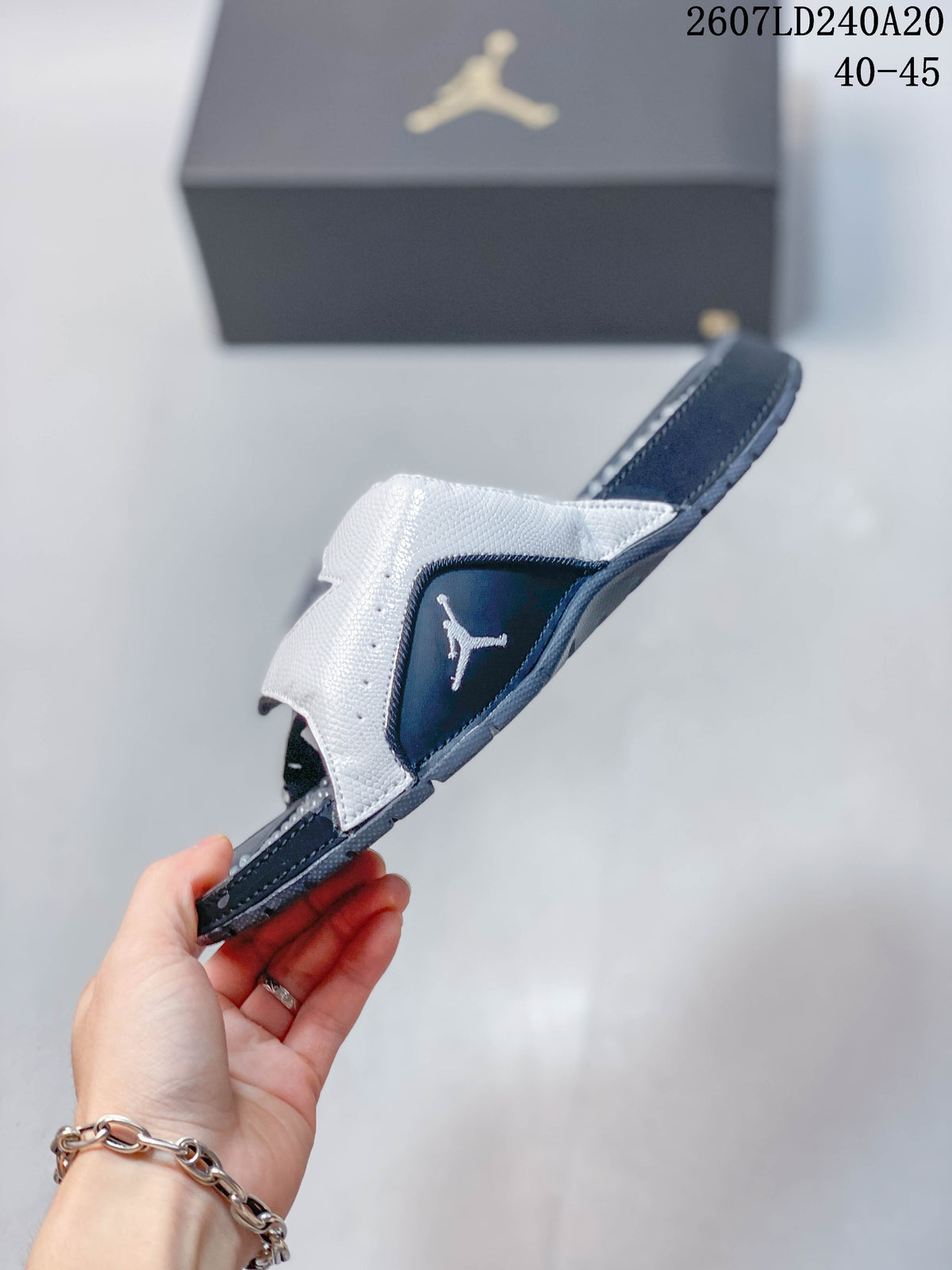 Side view of the slide with its adjustable strap lifted, showing the navy side panel and Jordan branding detail.