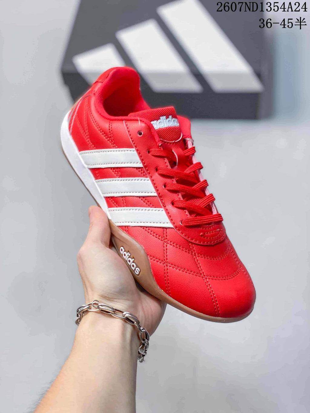 Angled close view of the red adidas sneaker showing the lace-up front, white stripes, stitching, and gum outsole.