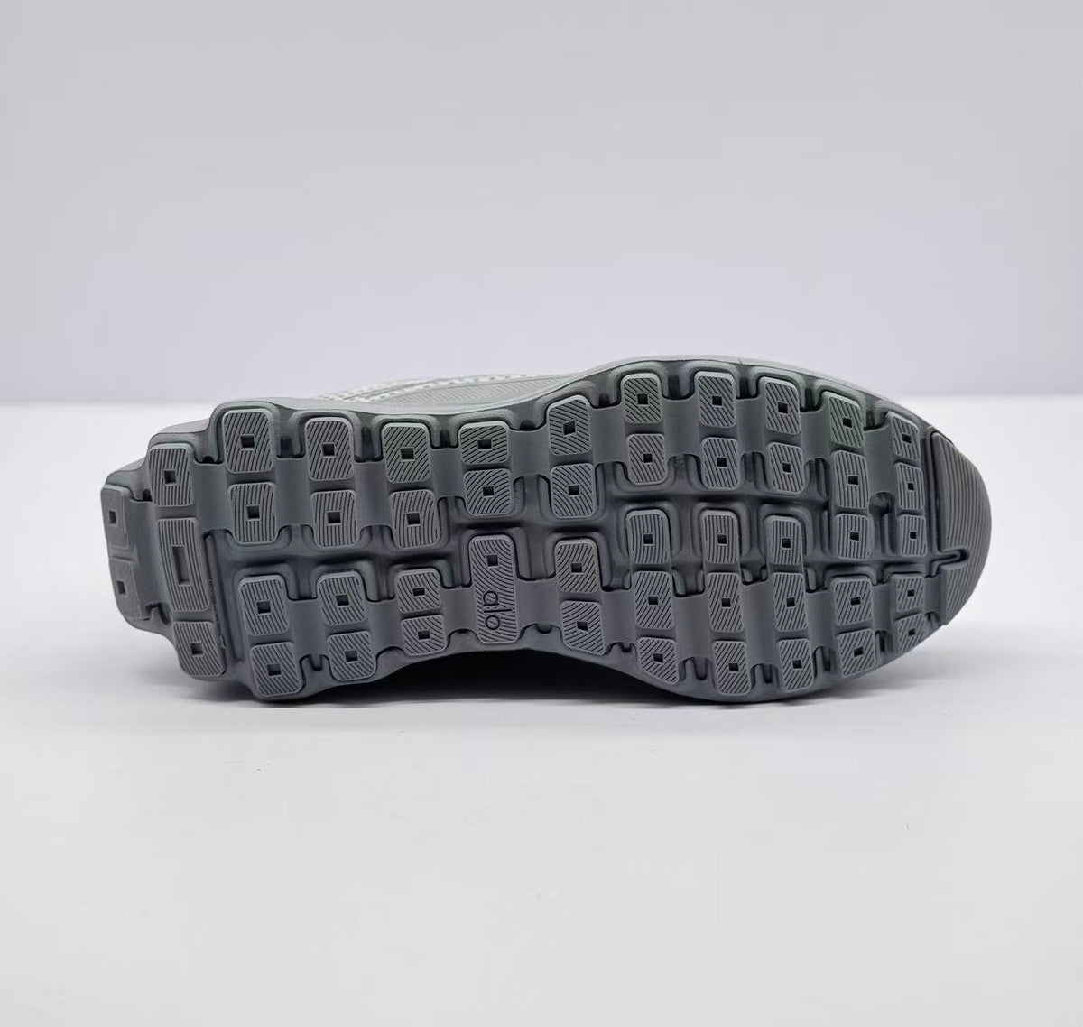 Underside view showing the segmented gray outsole with a lugged tread pattern and Alo branding.