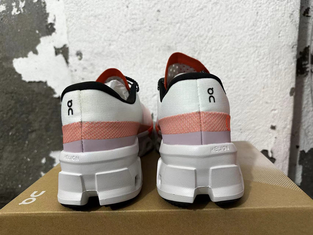 Rear view of white sneakers with orange-red accents, black trim, and chunky white soles