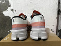 Rear view of white sneakers with orange-red accents, black trim, and chunky white soles