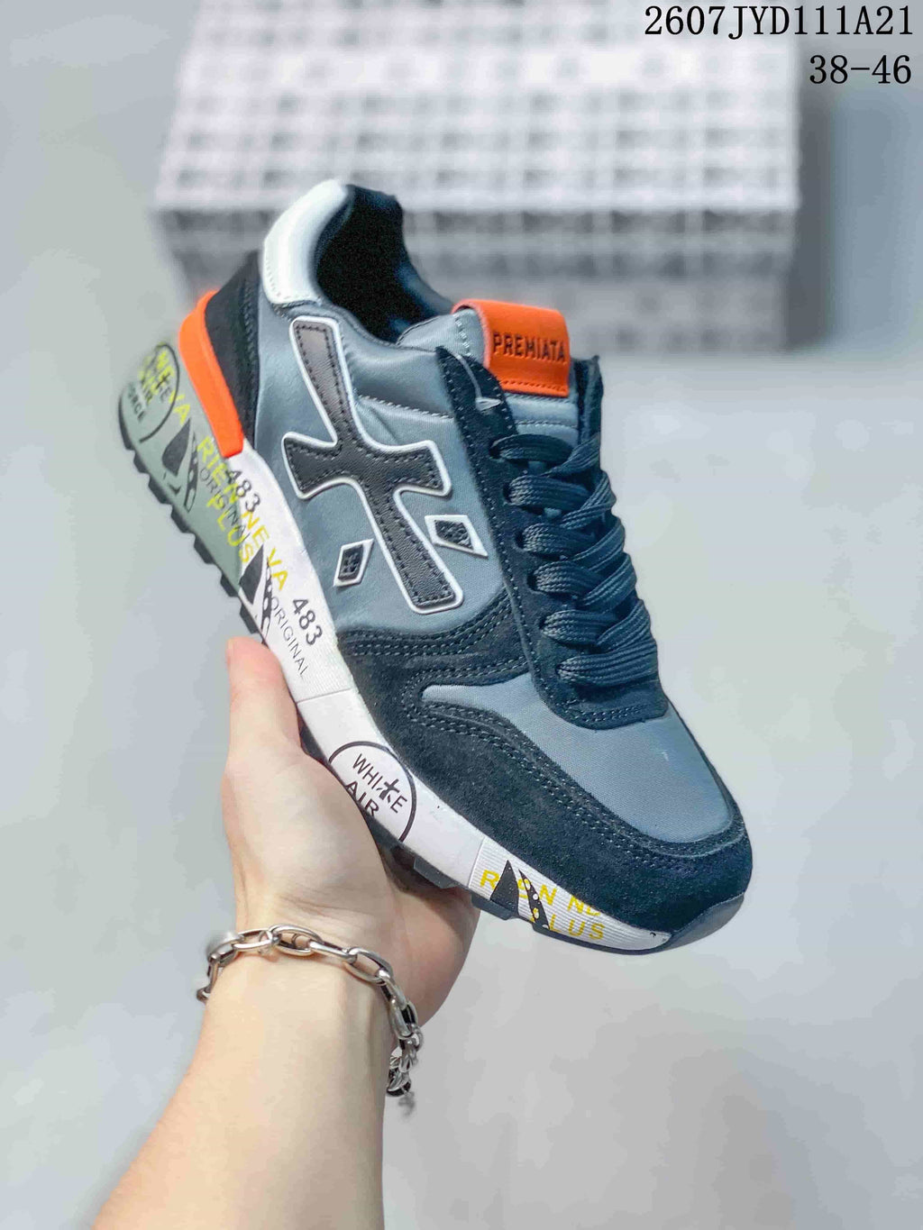 Angled side view of one grey, navy and orange Premiata sneaker with contrasting printed sole graphics.