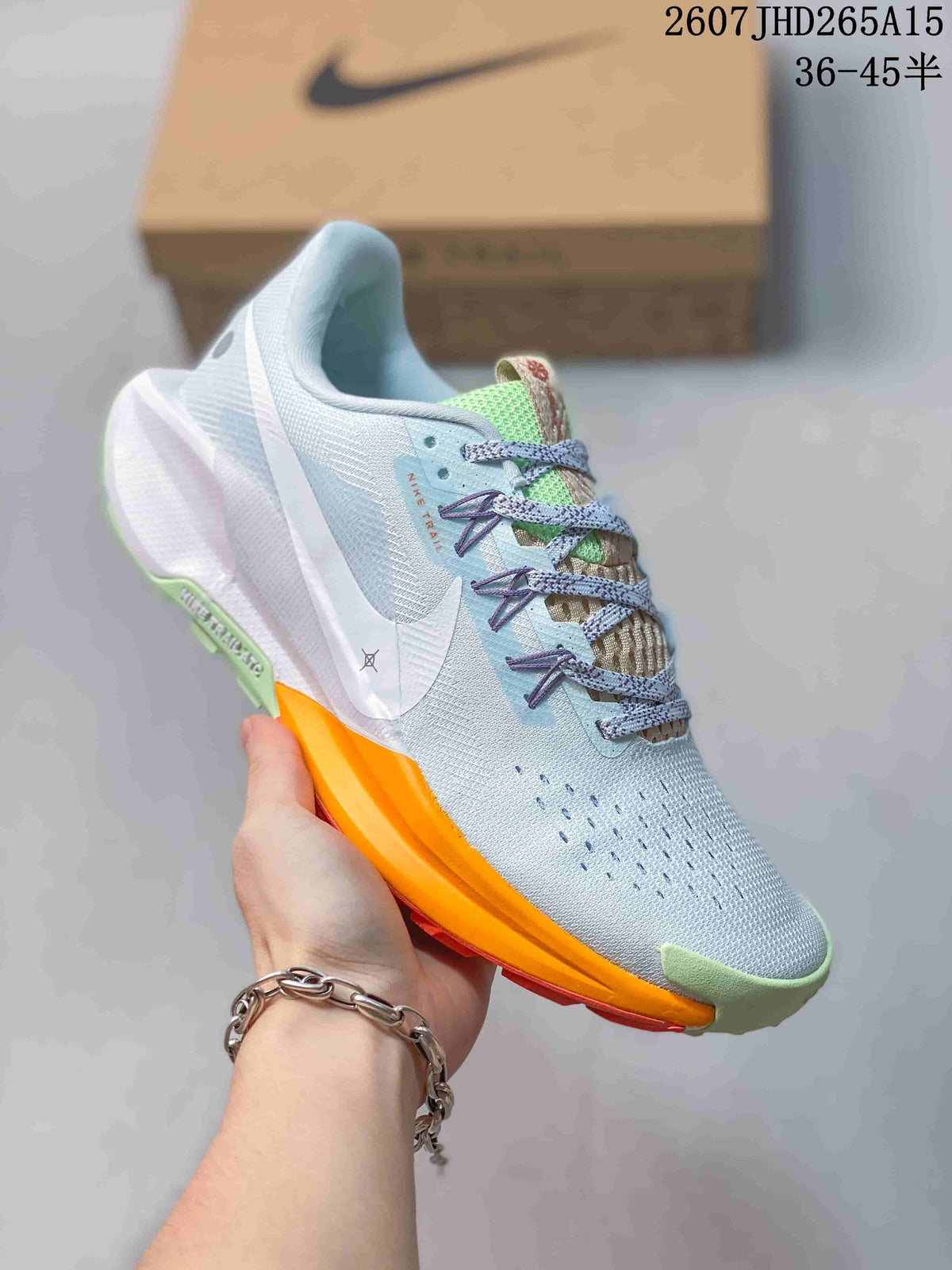 Angled side view of a Nike Pegasus Trail 5 sneaker showing the light blue upper, lace system, Nike Swoosh and orange outsole section.