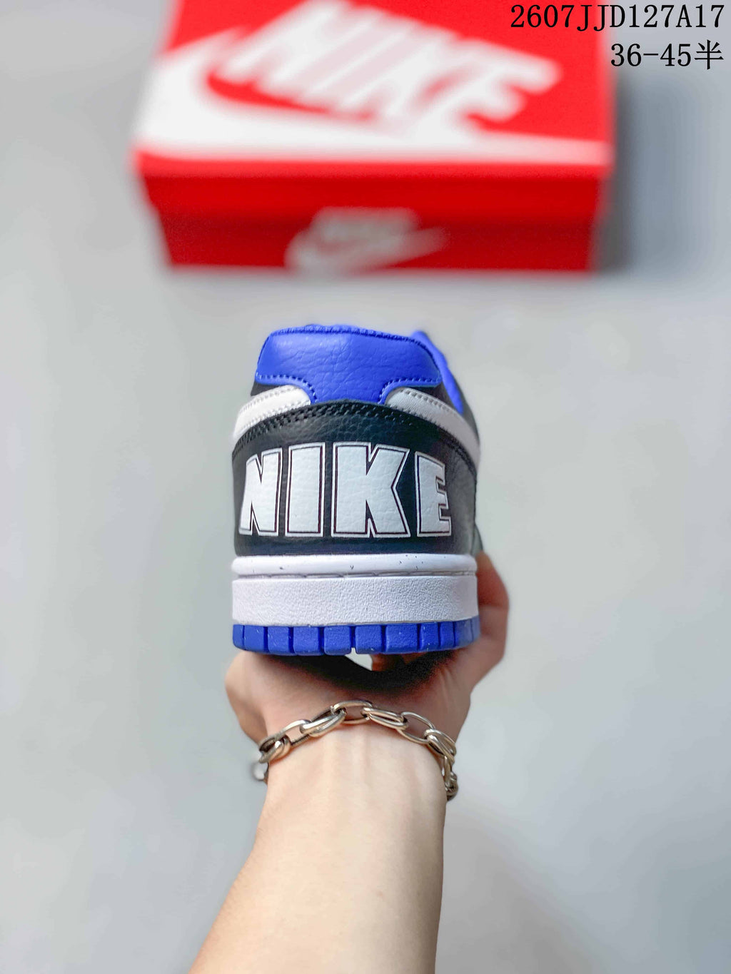 Rear view of the sneaker showing the contrasting heel branding, white midsole, and blue outsole.
