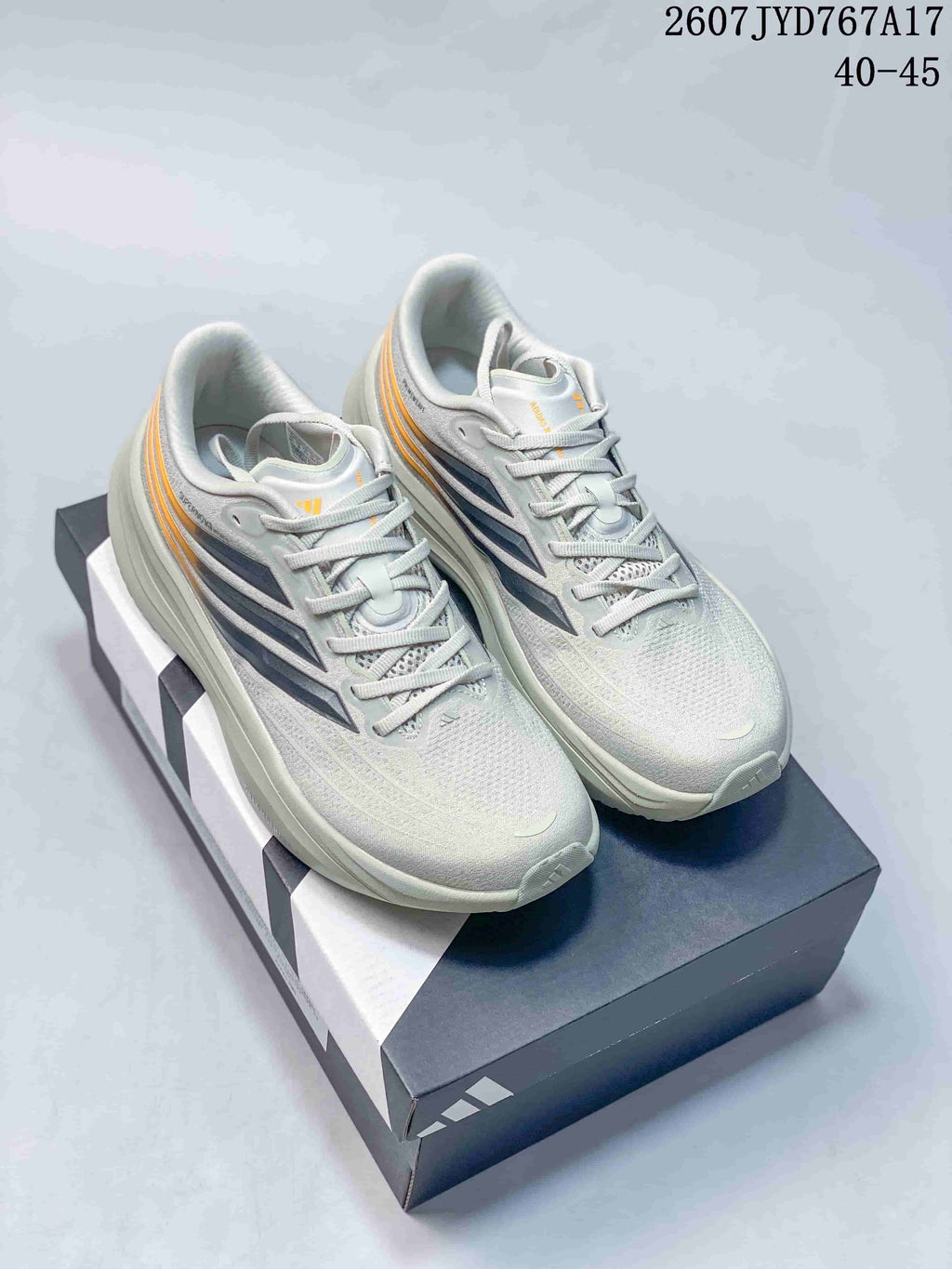 Pair of light gray adidas sneakers with navy and orange side accents displayed on an adidas shoebox; image text shows style code 2607JYD767A17 and sizes 40–45.