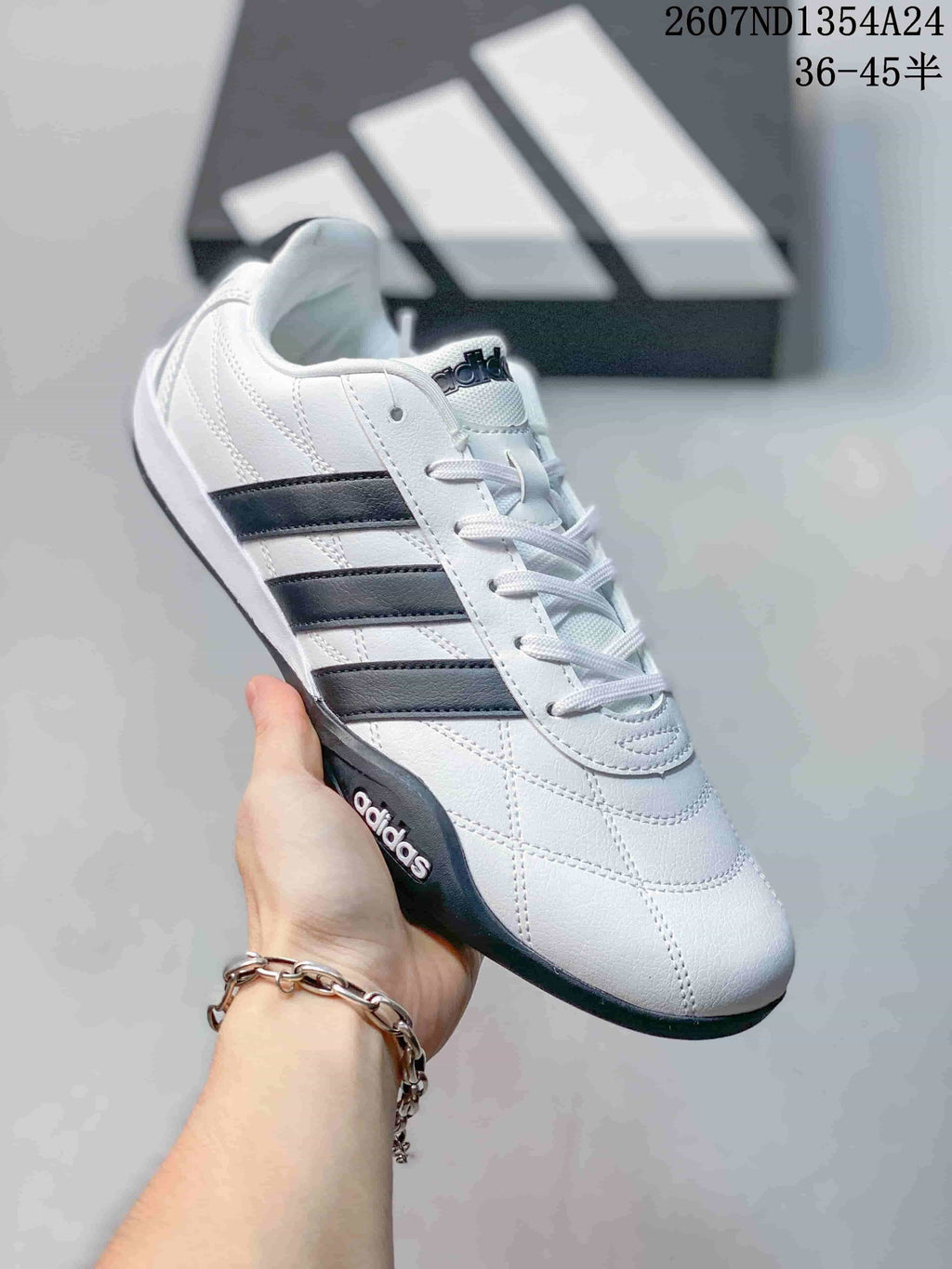 Angled side view of the white adidas sneaker with black three-stripe detailing and dark sole.