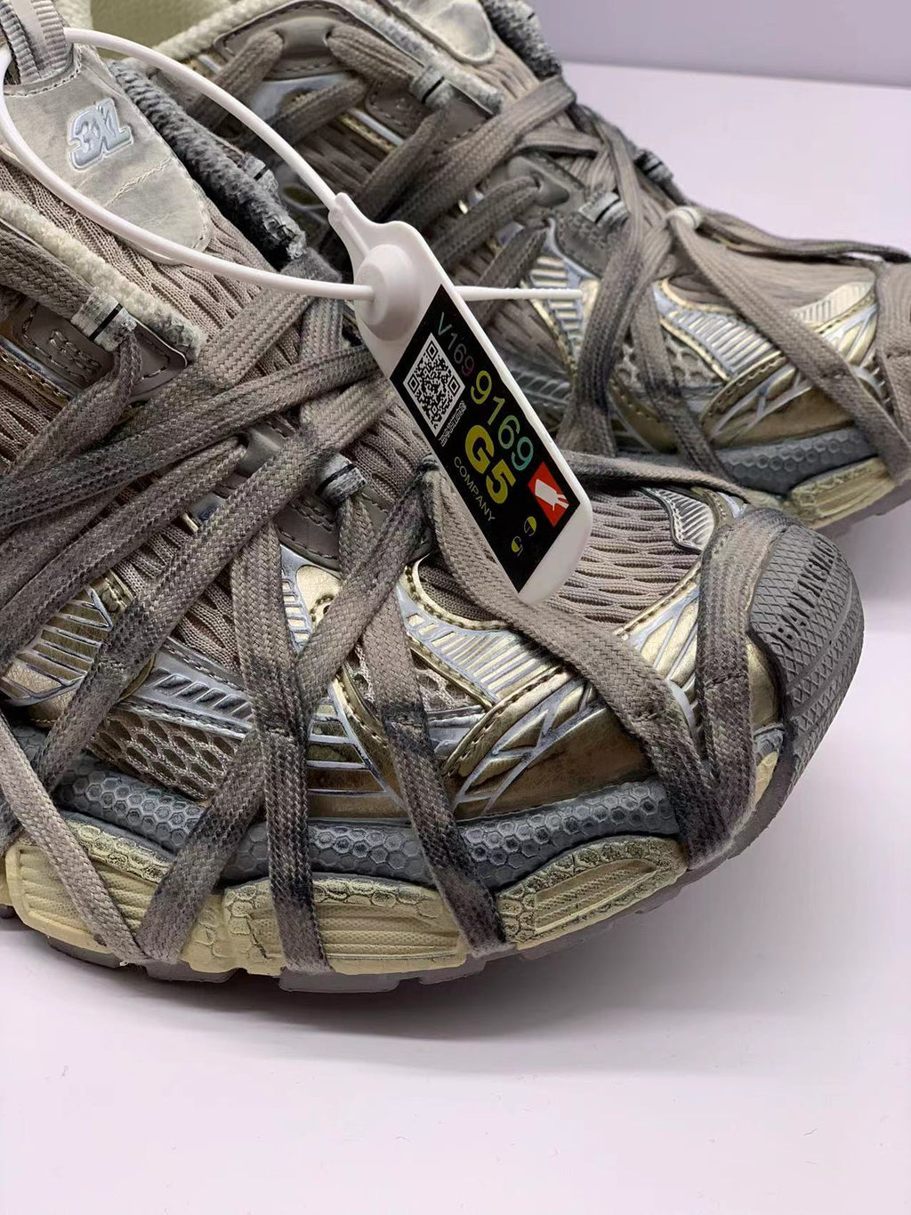 Close-up of the textured champagne and gray upper, overlapping laces, and attached tag.