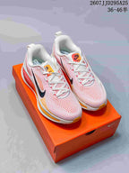 Pair of Nike Vomero 18 sneakers in pink and white displayed on an orange shoebox; the image shows style code TD295A25 and size range text.