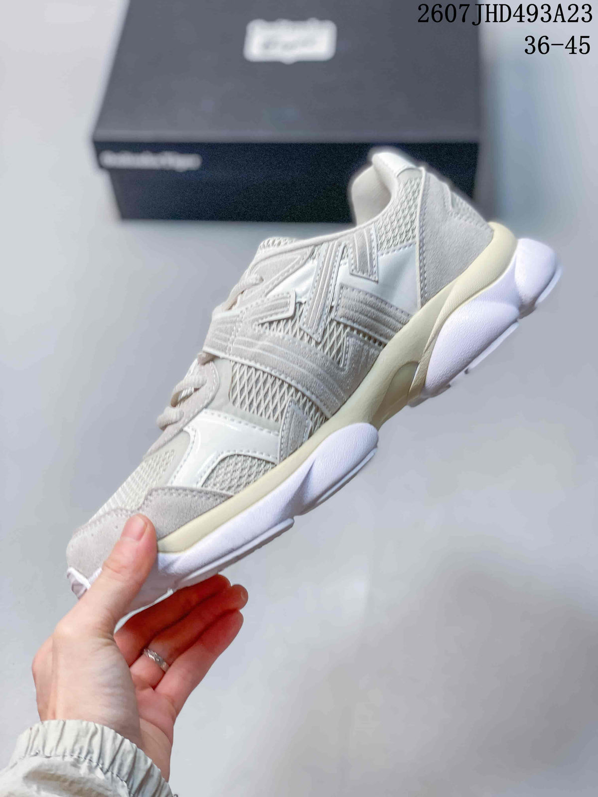 Side view of the white and gray sneaker showing layered overlays, mesh panels, and the raised sculpted sole.
