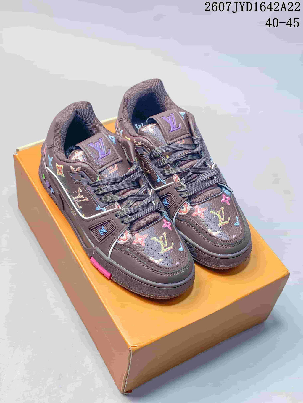 Pair of dark brown Louis Vuitton Trainer low-top sneakers with multicolor motifs displayed on an orange box; image text shows 2607 TYD1642A22 and 40–45.