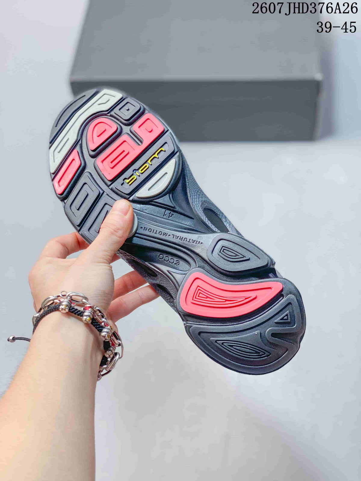 Underside of a black and gray sneaker showing the textured outsole with red, gray, and black sections.