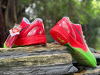 Rear and outsole views of the red and green basketball shoes, with a spare lace packet visible