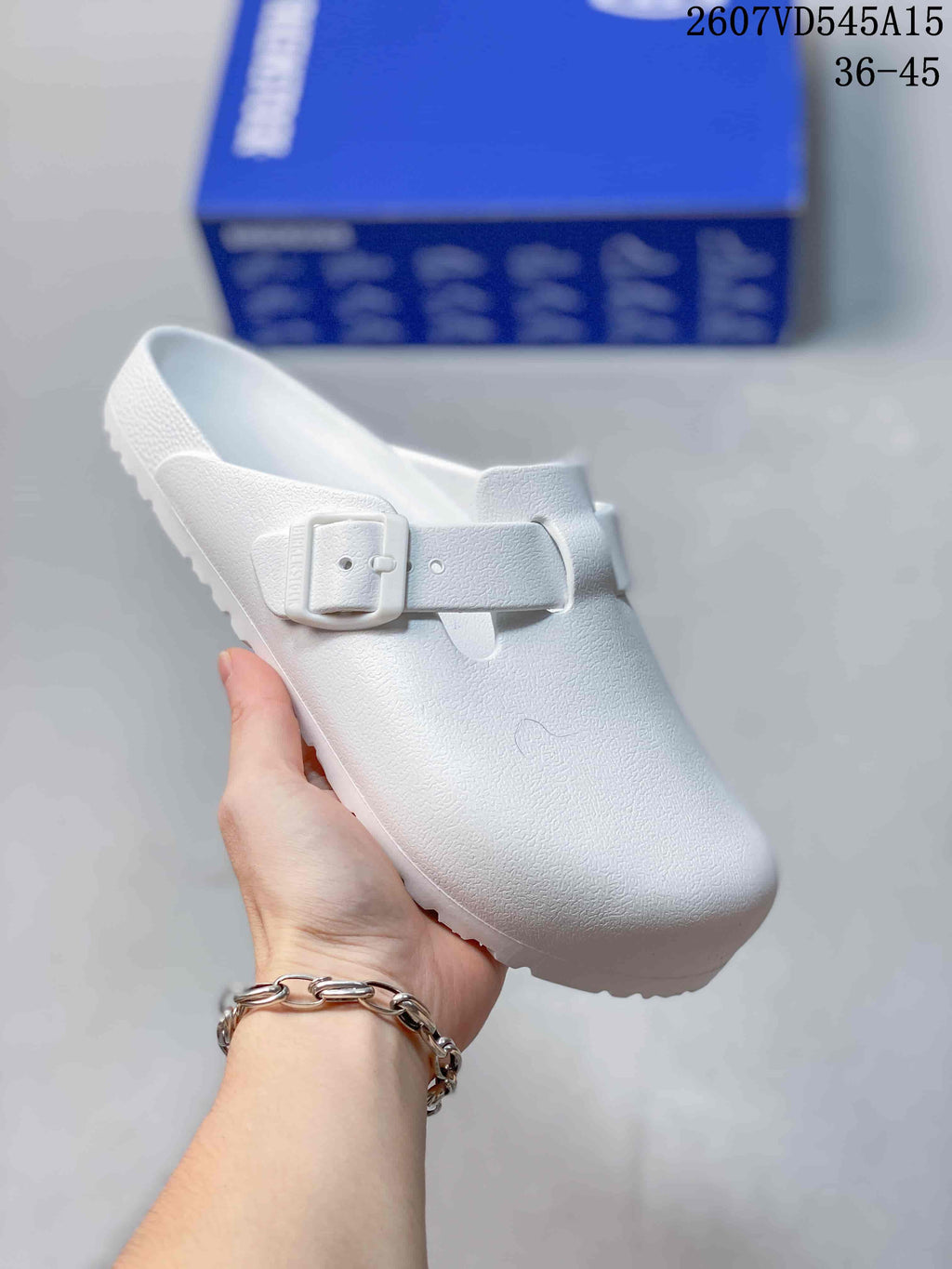 White closed-toe buckle sandal shown from above, highlighting the textured upper and adjustable strap.