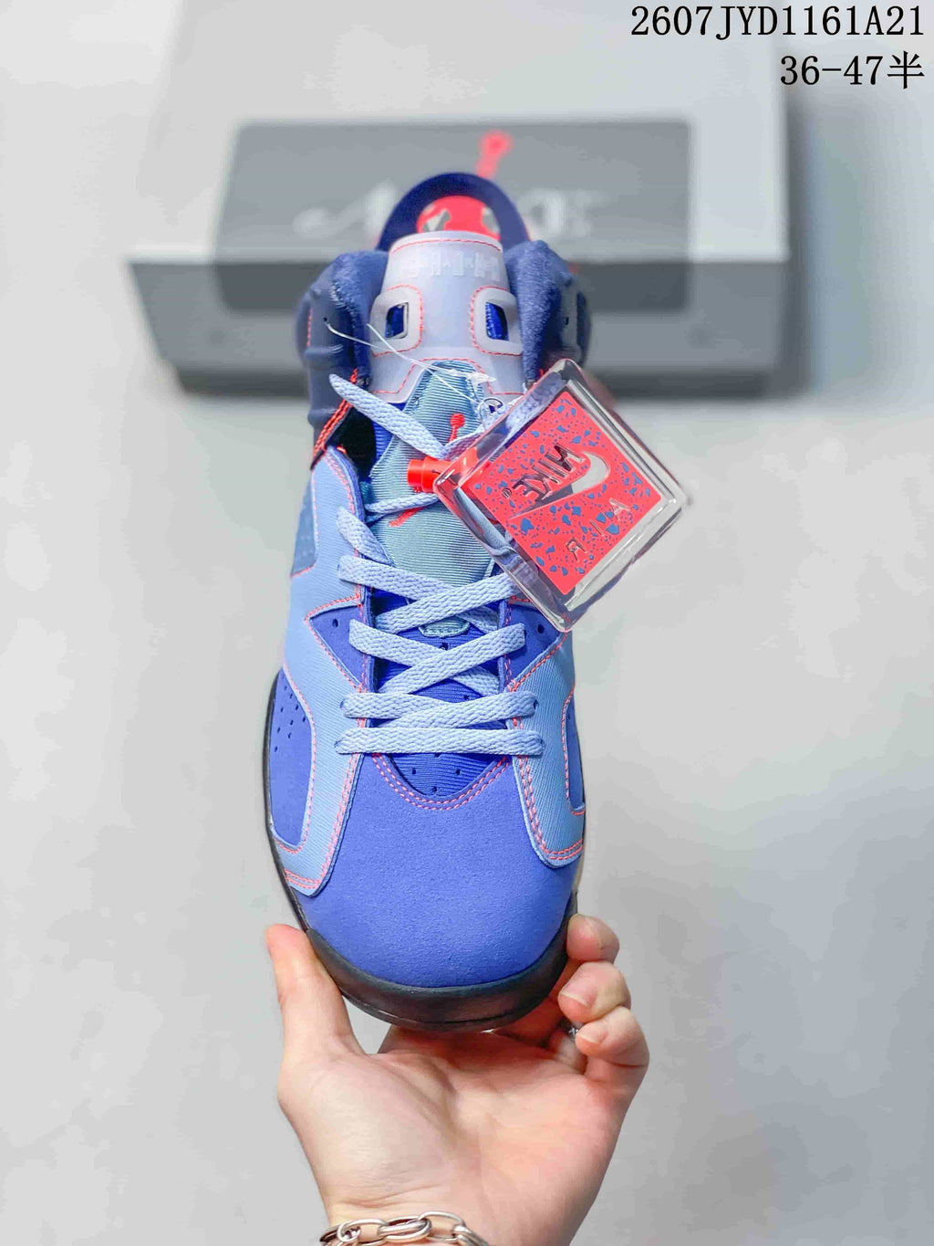 Front view of the blue high-top sneaker showing light-blue laces, red accents, perforated panels, and a branded hangtag.