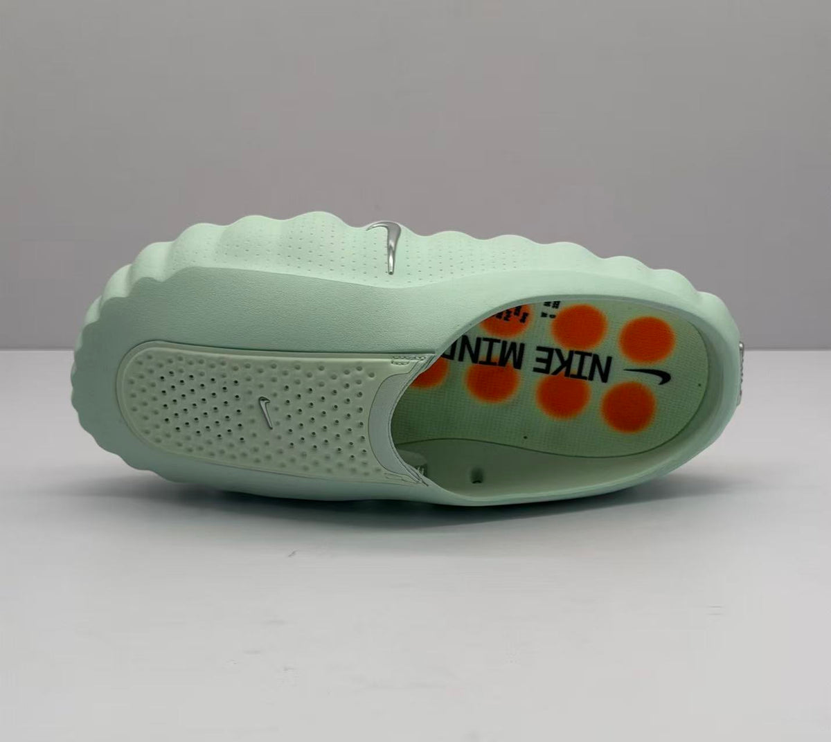 Top view of a light green slide showing the perforated upper panel and patterned footbed with orange graphics.