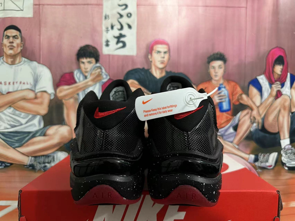 Rear view of black Nike basketball sneakers with red heel accents and a speckled midsole.