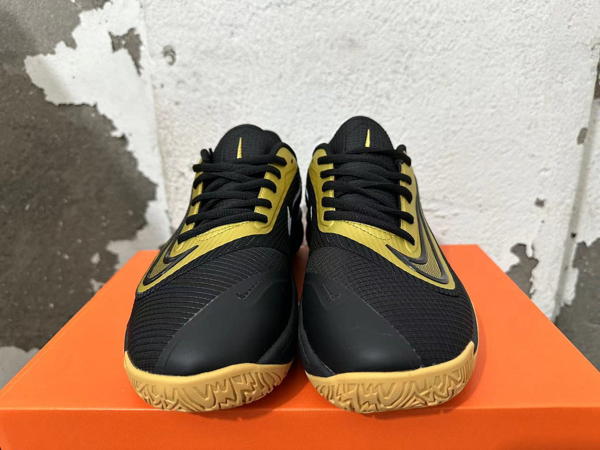 Front view of black and gold Nike basketball shoes with black laces and patterned soles.