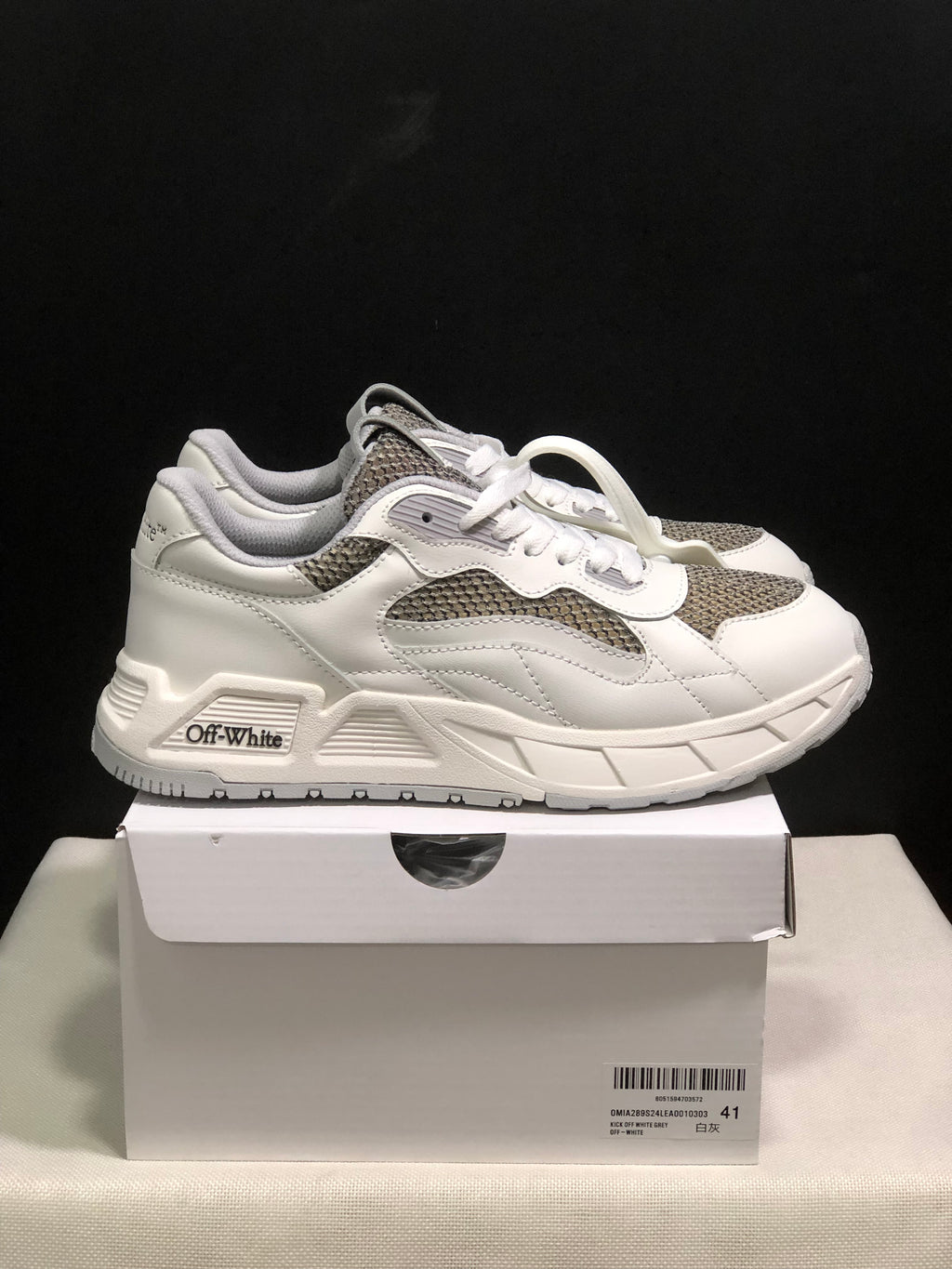 Side view of white and grey sneakers showing layered panels, textured inserts and Off-White side branding.