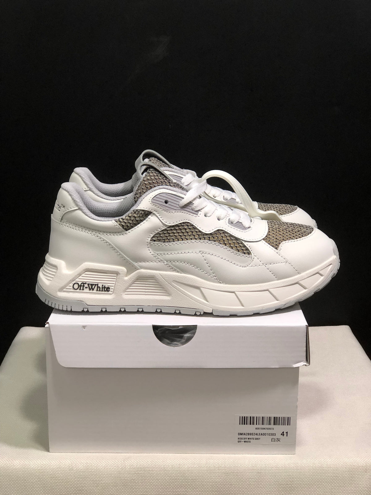 Side view of white and grey sneakers showing layered panels, textured inserts and Off-White side branding.