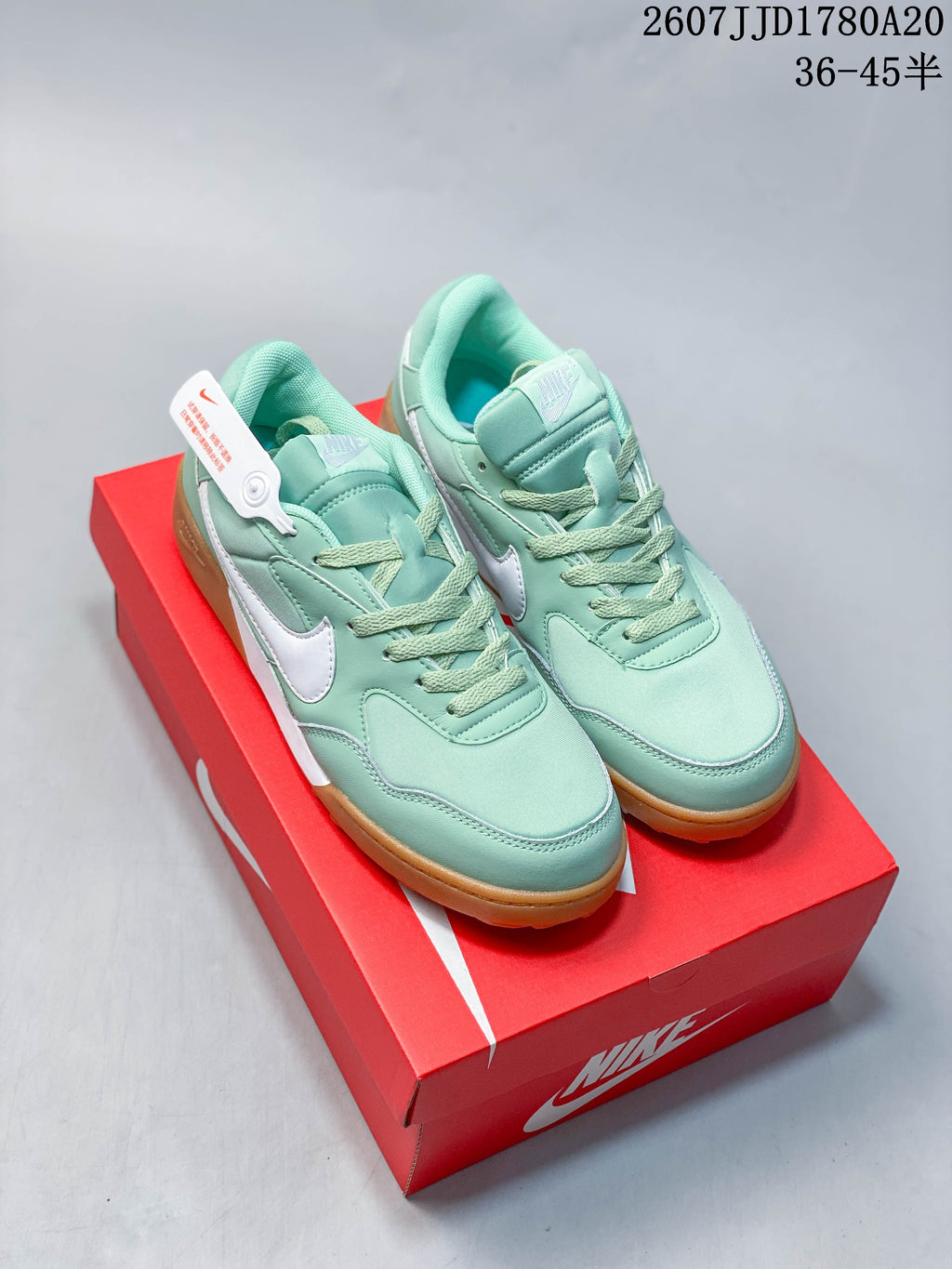 Mint green and white Nike sneakers displayed on a red shoebox, showing the gum outsole and padded lace-up design.