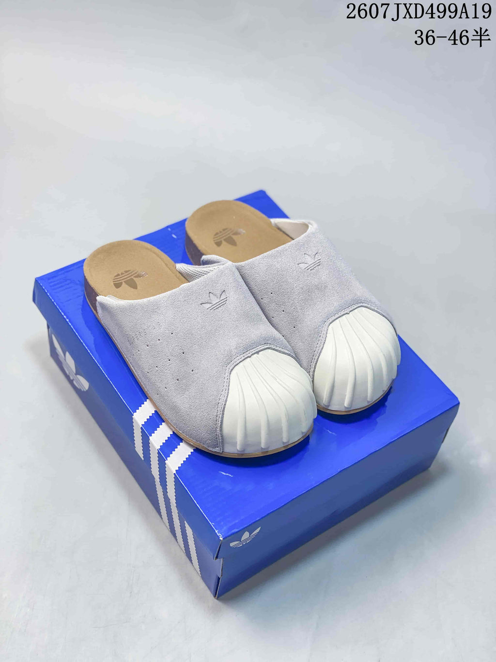 Light grey adidas Adimule mule slides with ribbed white toe details displayed on a blue adidas-style shoebox.