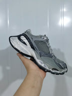 Gray, silver and black mesh sneaker shown from the outer side with a layered white midsole.