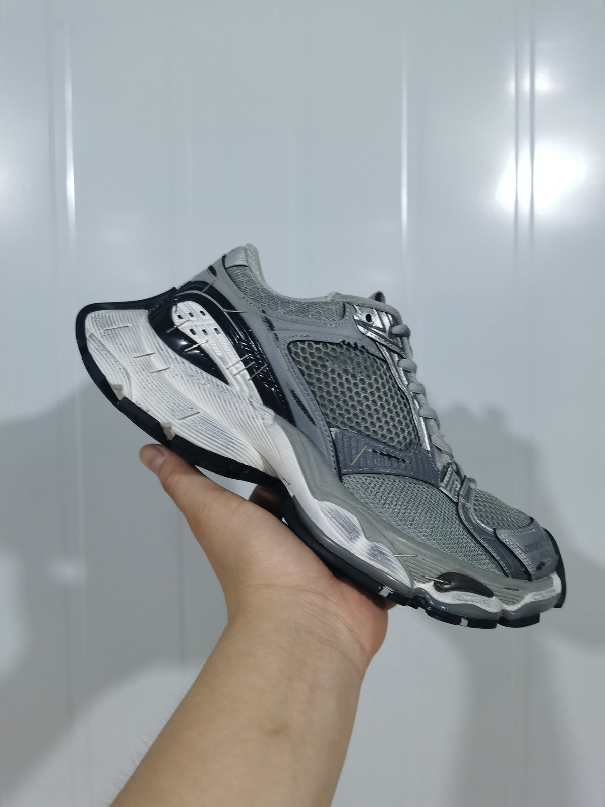Gray, silver and black mesh sneaker shown from the outer side with a layered white midsole.