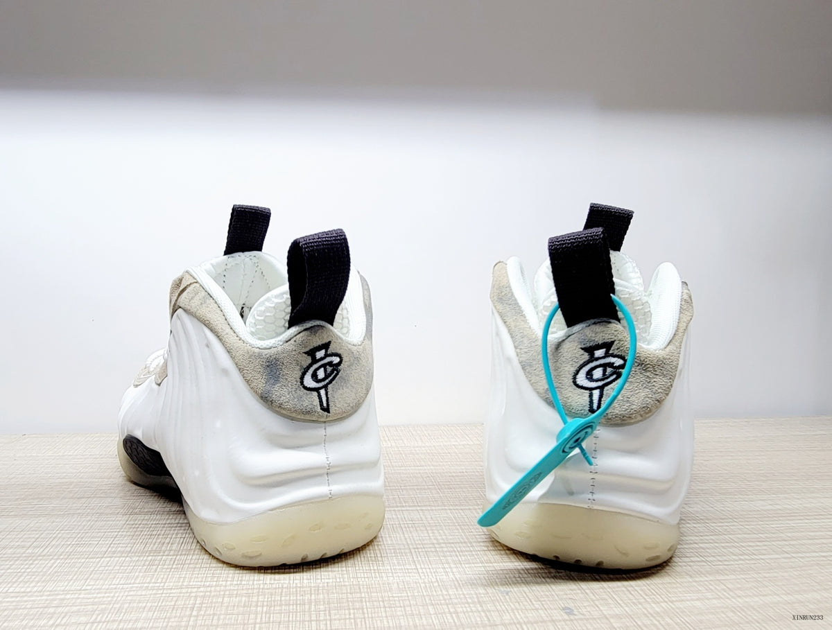 Rear view of white Nike Air Foamposite One sneakers with beige and gray marbled heel accents and black pull tabs.