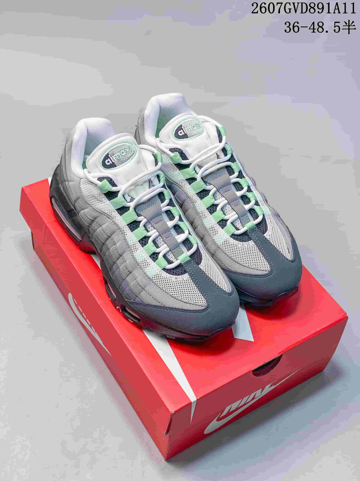 Pair of gray, black, white, and green Nike Air Max 95 sneakers displayed on a red shoe box; size range text is visible at the top.
