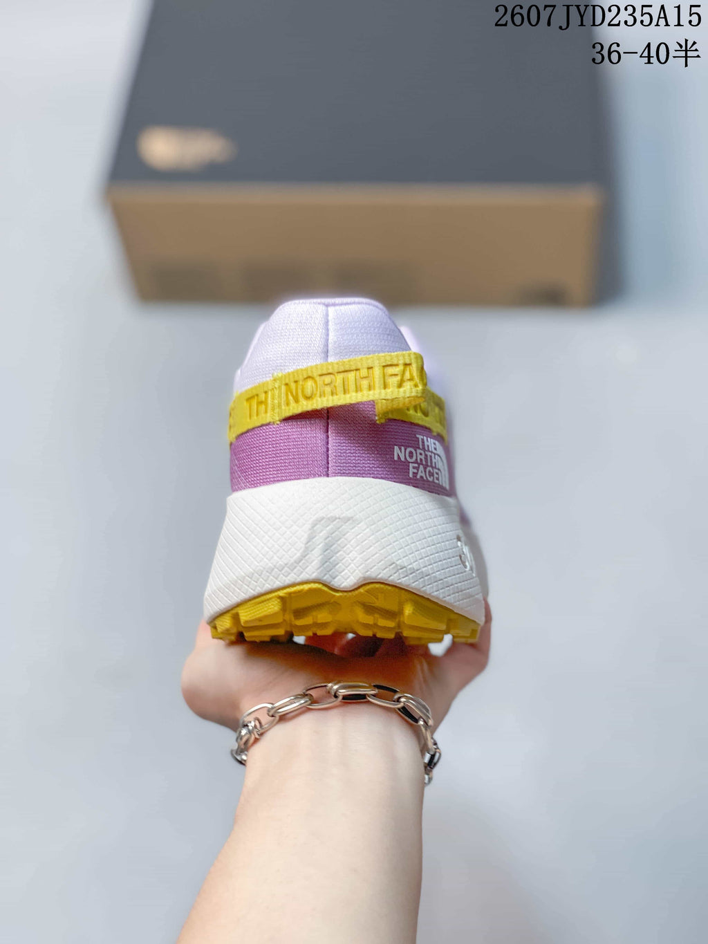 Rear view of the shoe showing the padded collar, purple heel panel, yellow pull tab, and yellow outsole.