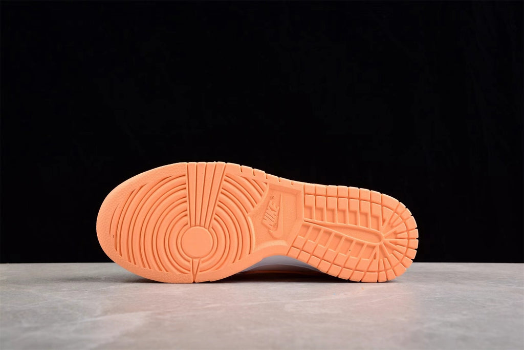 Bottom view showing the orange rubber outsole with circular forefoot and grid-like tread patterns.