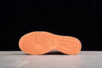 Bottom view showing the orange rubber outsole with circular forefoot and grid-like tread patterns.